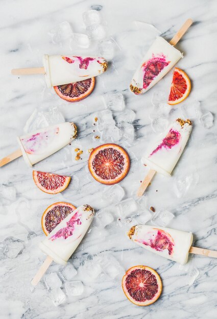 Blood orange yogurt and granola popsicles on ice cubes