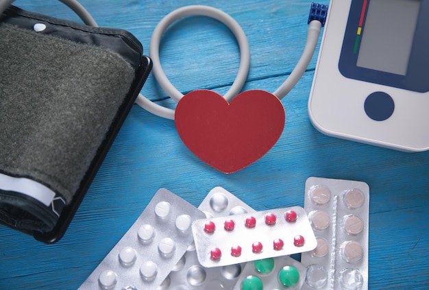 Blood pressure meter and pills on the blue background.