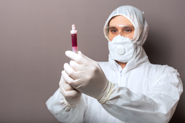 Blood test in doctors hands. Doctor in protective medical suit biological hazard medical mask