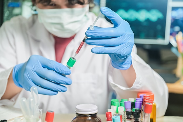 Blood test tube in Medical Scientist hand with syringe mixed specimen in Laboratory room at hospital, blood test tube for analysis for diagnosis illness results