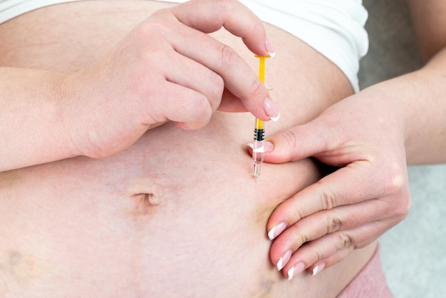 Blood thinners concept close up of pregnant woman making injection in stomach