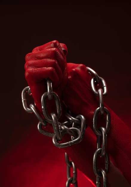окровавленные руки, сжатые в кулаки в кандалах металлической цепи, символизируют протест рабства и борьбу за свободу