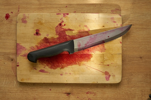 Bloody butchers knife on a wooden surface.