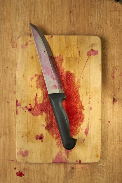 Photo bloody butchers knife on a wooden surface.