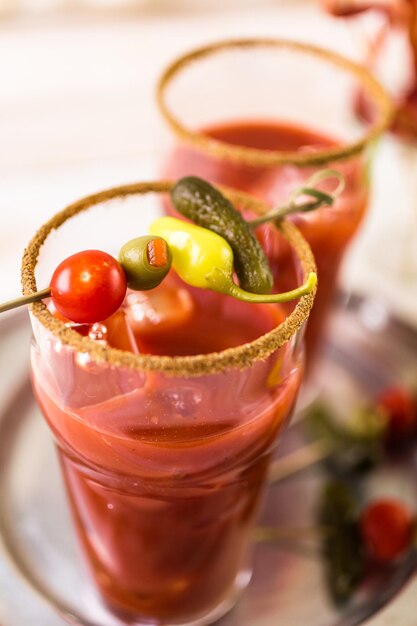 Bloody mary cocktail garnished with celery sticks, olives, and bacon strips.