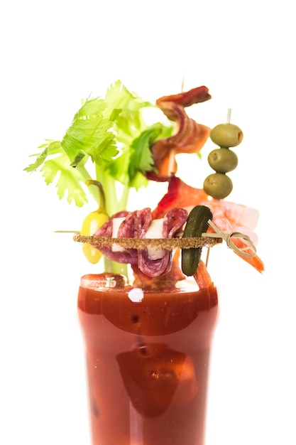 Bloody mary cocktail garnished with celery sticks, olives, and bacon strips.