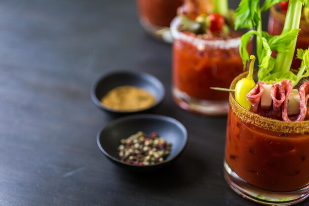 Bloody mary cocktail garnished with celery sticks, olives, and bacon strips.