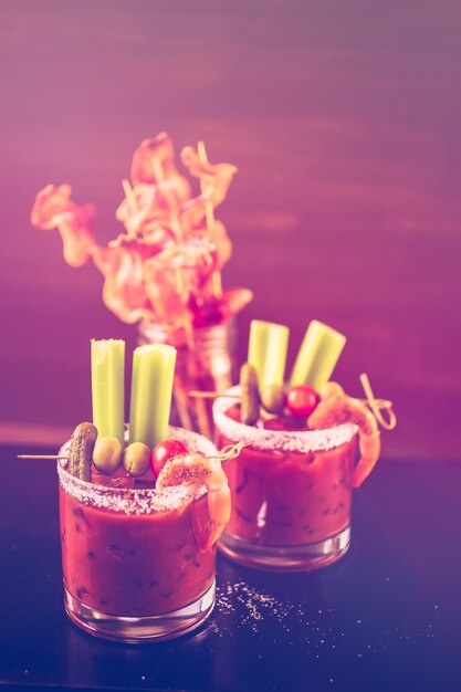 Bloody mary cocktail garnished with celery sticks and olives.