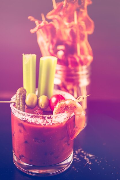 Bloody mary cocktail garnished with celery sticks and olives.