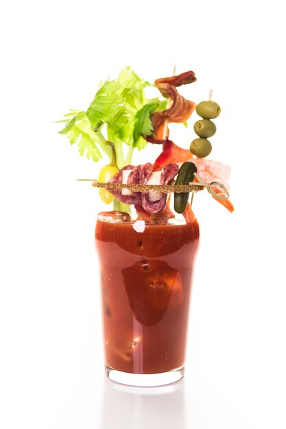 Bloody mary cocktail gegarneerd met stengels bleekselderij, olijven en spekreepjes.