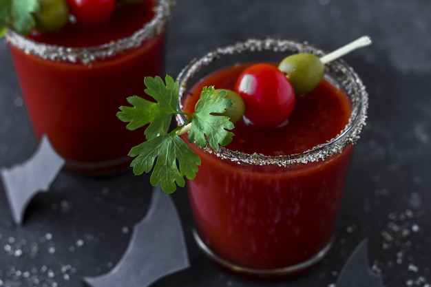 Bloody Mary cocktails served with pickled veggies (tomatos, olive and celery) and paper bats. closeup, copy space