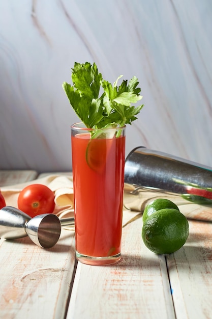 Bloody or virgin mary cocktail served in a cup with celery sticks on a wooden table