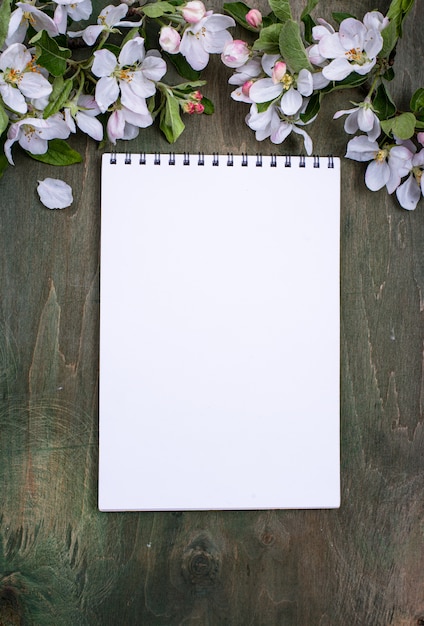 Photo blooming apple tree and blank notebook