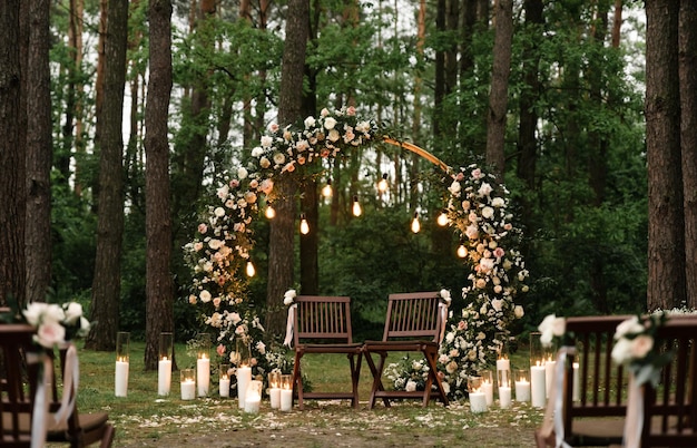 Blooming decoration of wedding arch with roses, carnation and eucalyptus. Beautiful wedding ceremony outdoors. White and pink colors. Wedding photo zone. Floral concept. Wedding details