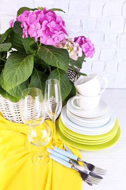 Blooming hydrangea and utensils on table on grey wall background