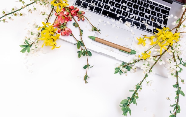 Foto la molla di fioritura dell'ufficio del computer portatile del taccuino fiorisce lo spazio bianco della copia di rosa del ramo della mela