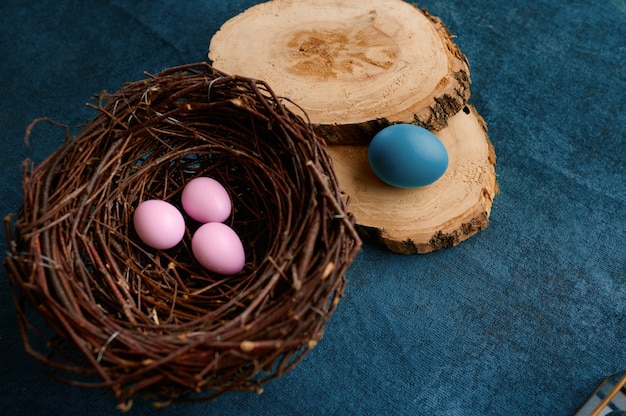 Blooming willow branch, easter eggs in nest and tableware on blue cloth background