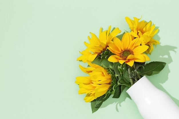 Фото Цветущие желтые цветы подсолнуха в белой вазе плоская лежала с летними цветами