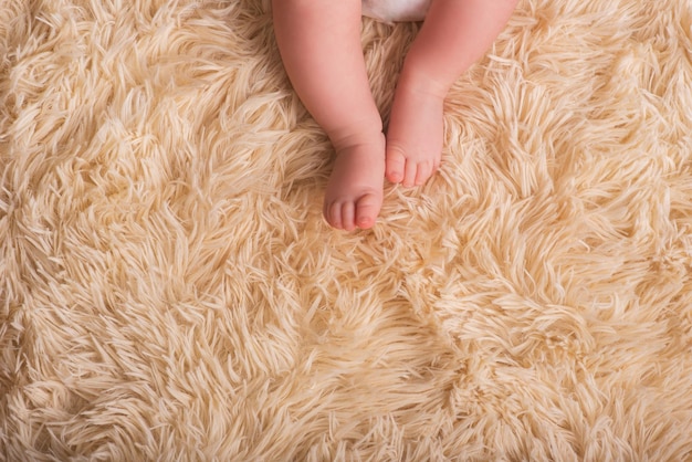 Blote benen van een pasgeborene op een donzige, lichte, warme bekleding van één ton. Schattige pasgeboren baby voeten close-up. Plaats voor tekst, copyspace