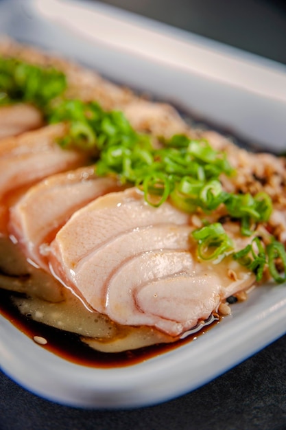 Сашими из лосося с паяльной лампой с кунжутом, шою и соусом из маракуйи на черном столе. Крупный план.