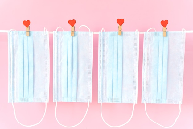 Photo blu protective face masks hanging on clothespins with hearts on rope