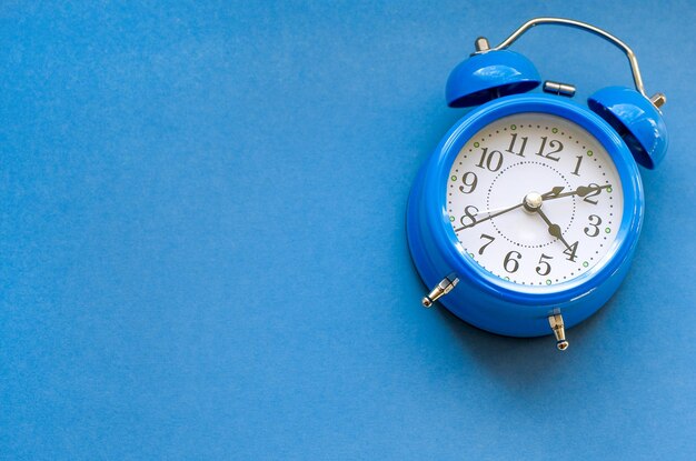 Blue alarm clock on blue background