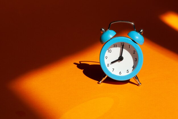 Blue alarm clock on orange background. Wake up alert Morning concept.