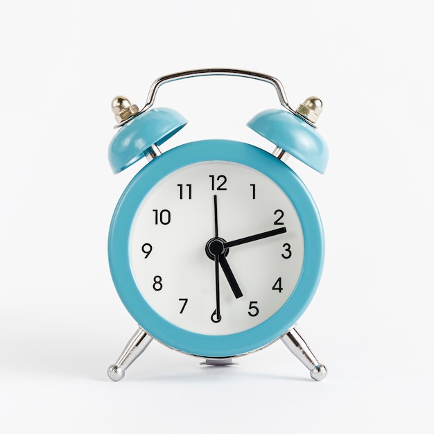 Blue alarm clock on white wall. Time and deadline concept