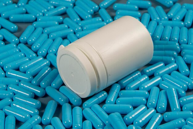 Foto capsule antibiotiche blu consistenti con bottiglia bianca produzione farmaceutica salute globale resistenza agli antibiotici capsule di gelatina