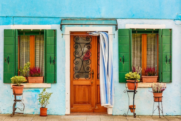 Blue aqua colored house with flowers and plants. Colorful houses in Burano island near Venice, Italy. Venice postcard.