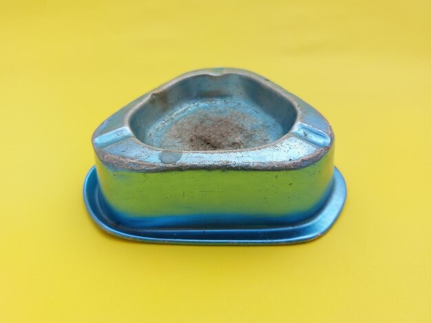 Photo blue ashtray isolated on yellow background