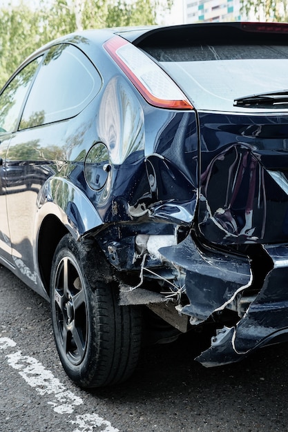 Photo blue automobile with a big dent on the rear hood.