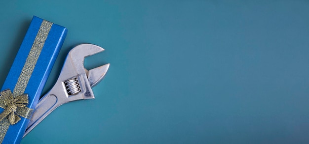 Photo on a blue background, a blue gift box with a wrench, the concept of a gift to a guy, a man. new year's gift, birthday. banner