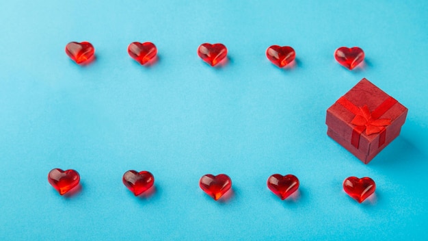 On a blue background a box with a gift decorated with hearts and pebbles save a place