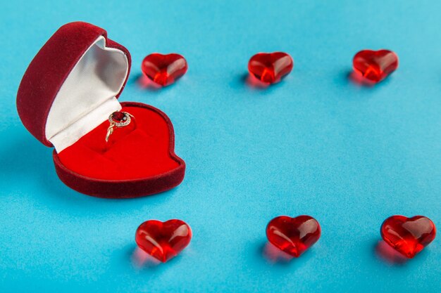 On a blue background a box with a ring decorated with hearts and pebbles horizontal photo