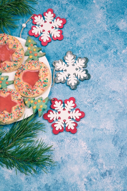 On a blue background a plate with handmade Christmas cookies and Christmas snowflakes