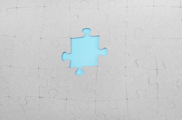회색 퍼즐의 누락된 조각을 통해 빛나는 파란색 배경