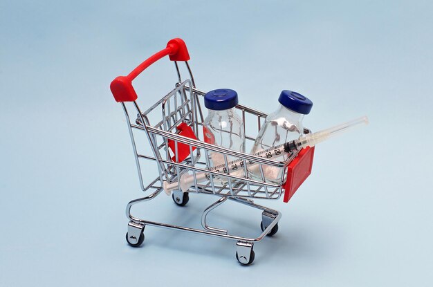 On a blue background a supermarket trolley filled with a vaccine and a syringe