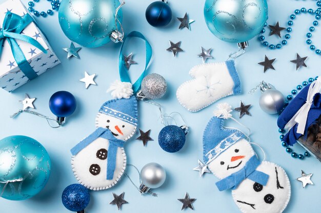 Blue background with christmas balls, felt snowman, mitten and decorations