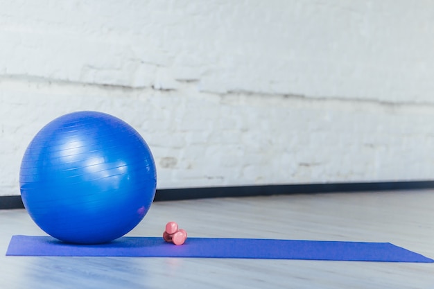 Blue ball and dumbbells in a gym room