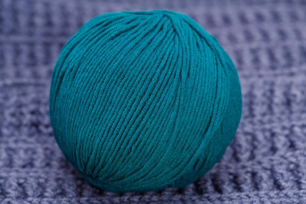 A blue ball of wool lies on a blue woolen tablecloth. high\
quality photo