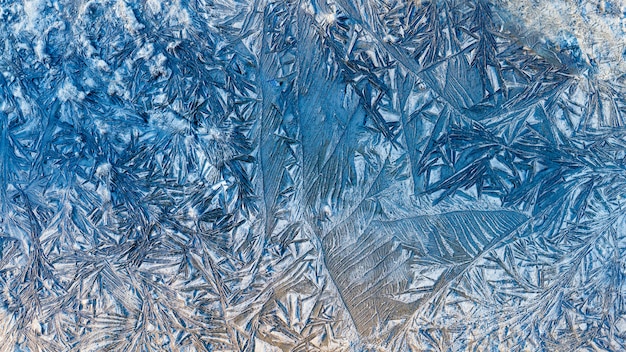 Blue beautiful winter frost patterns, abstract frost flowers texture on the road