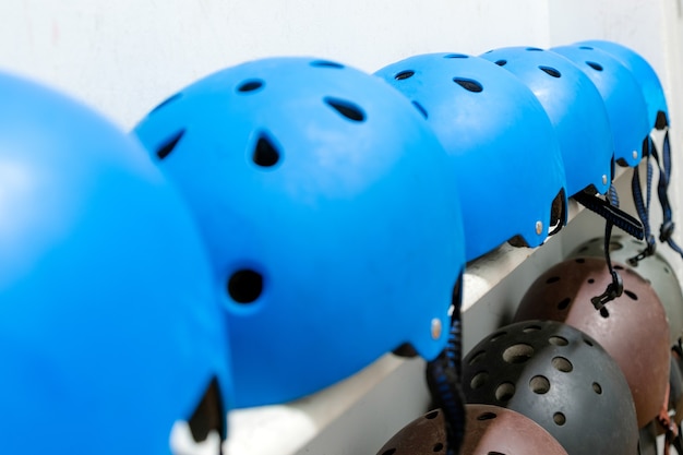 Blue, black and brown extreme sport helmets on the shelf with white background.