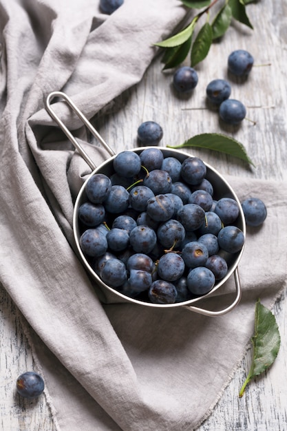 Blue blackthorn berries in metallic bowl on a table