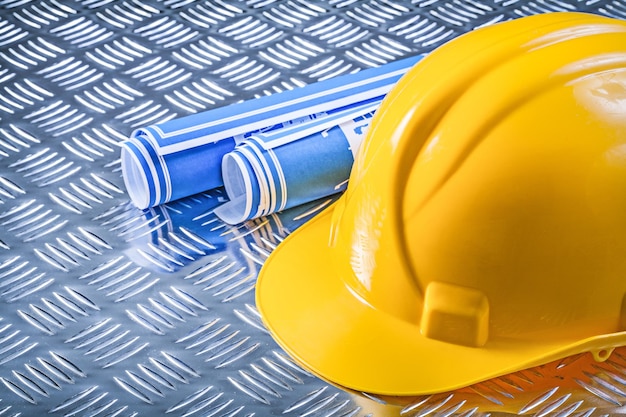 Blue blueprint rolls hard hat on corrugated metal background construction concept