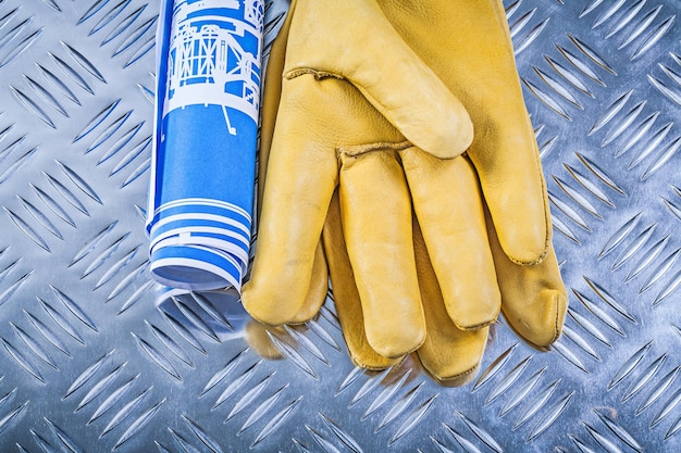 Blue blueprints leather safety gloves on fluted metal background construction concept