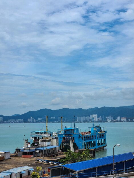 Photo a blue boat is docked in front of a cityscape.