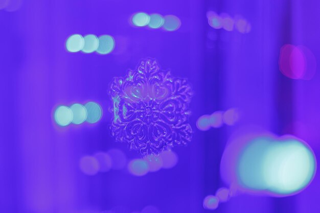 Blue bokeh on a lilac background with a blurred snowflake glittering lights are not in sharpness