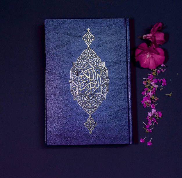 A blue book with gold lettering on the cover and a flower next to it.