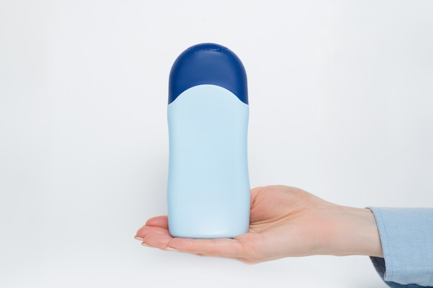 Blue bottle for cosmetic product in a female hand.